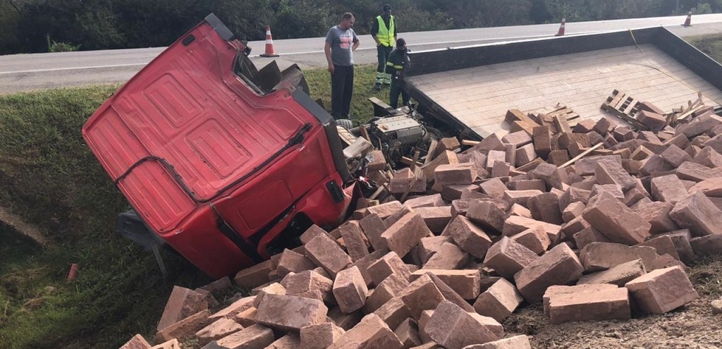 CAMINHO TOMBA E TEM CABINE DESTRUDA POR CARGA DE PEDRAS, NA BR 116, EM CAMAQU